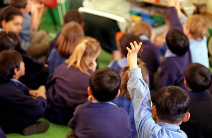 School children sitting with hands up