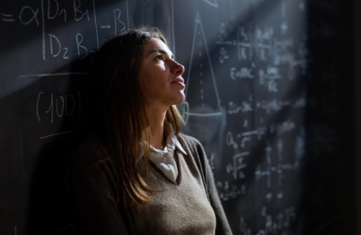 cinematic_shot_of_young_pensive_thoughtful_female_teacher_leaning_against_blackboard_2